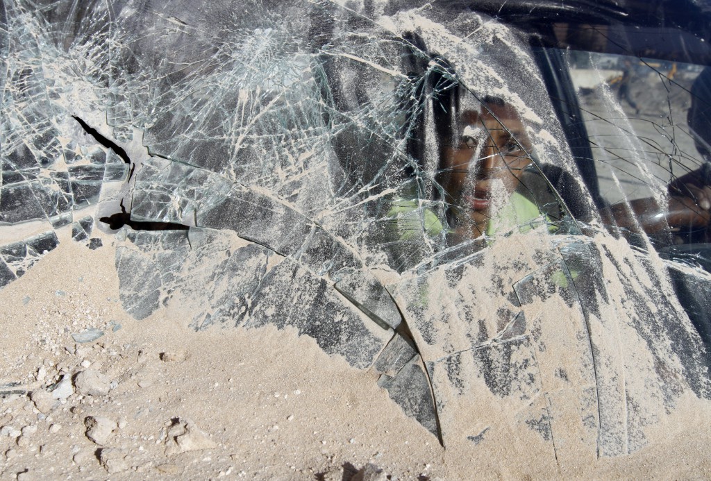 A young boy looks through broken glass a