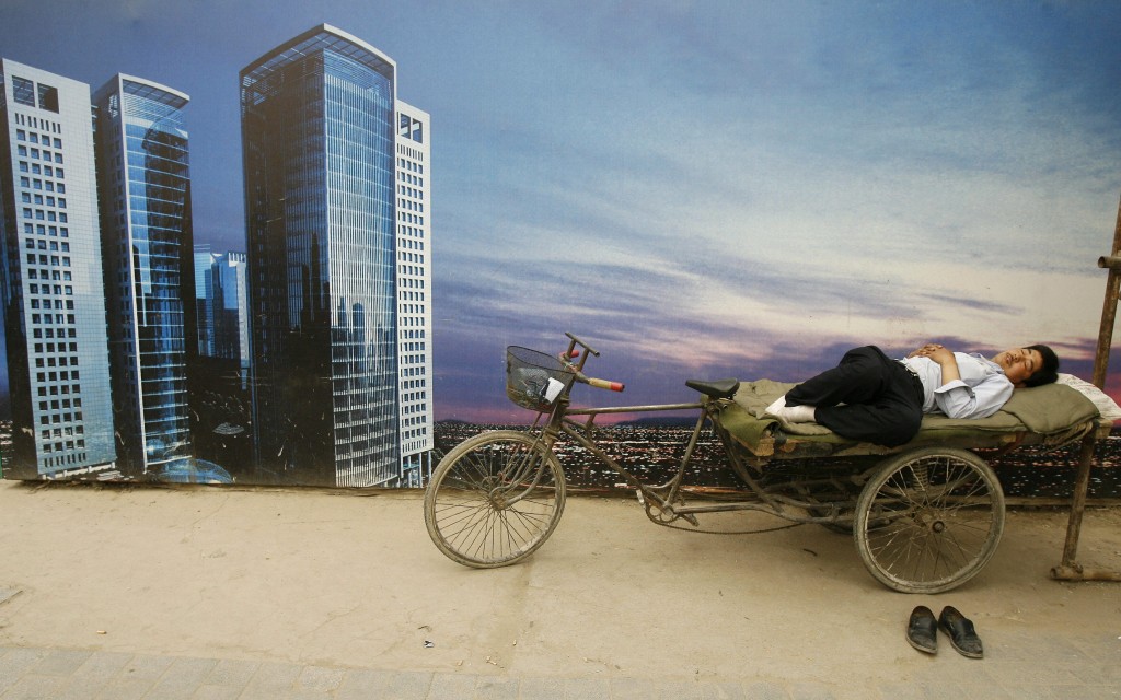 A man sleeps on his flatbed tricycle in